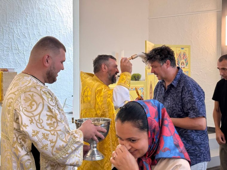 Der Priester besprengt die Gläubigen mit Weihwasser, ein Altardiener hält die Schale