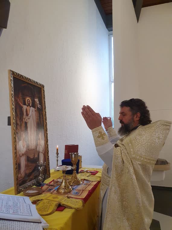 Священник із піднятими руками молиться перед іконою Воскресіння