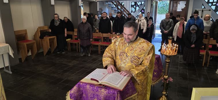 Священник читає з розкритого Євангелія, громада стоїть навколо